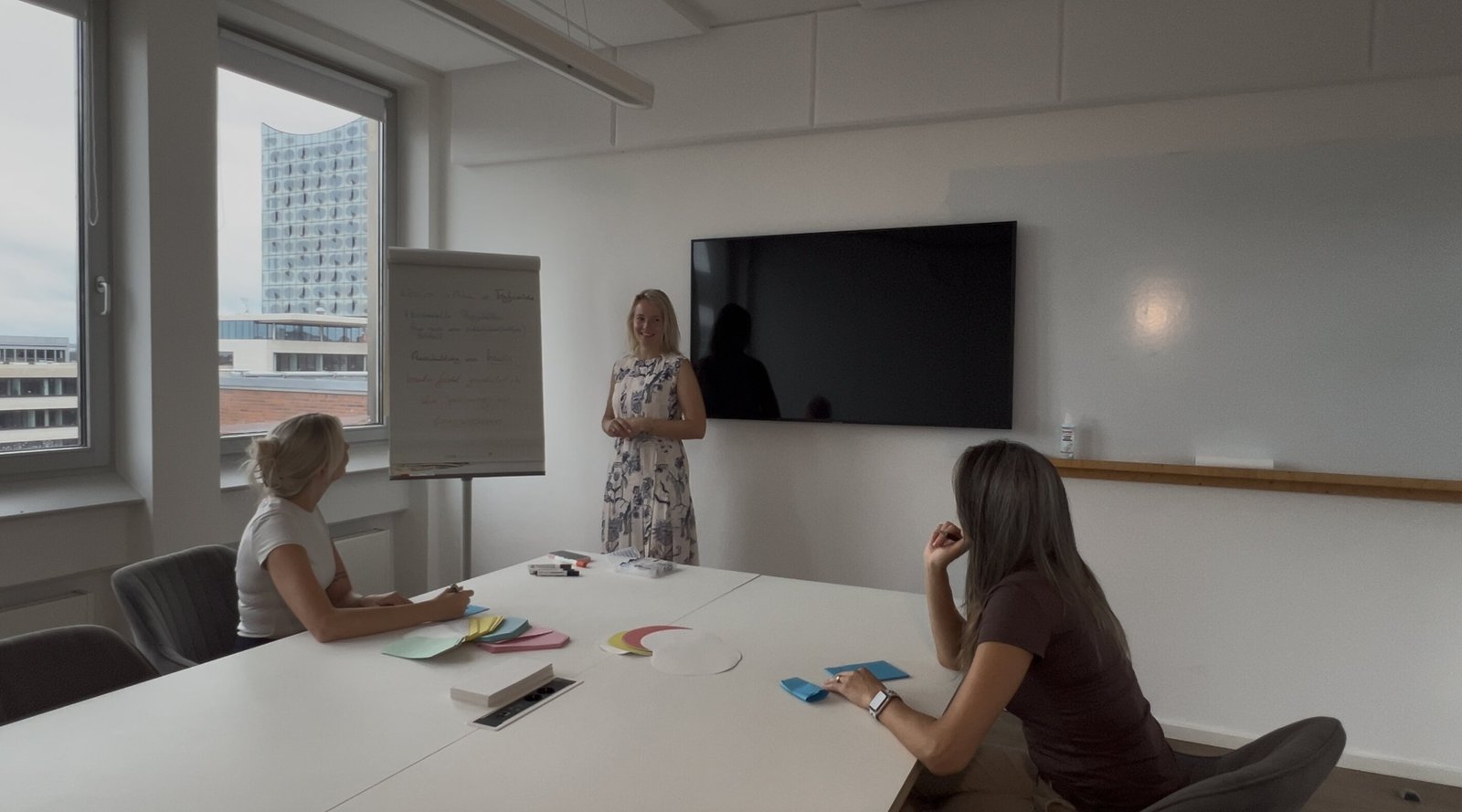 Stefanie hält ein Seminar für eine kleine Gruppe, im Hintergrund die Elbphilharmonie